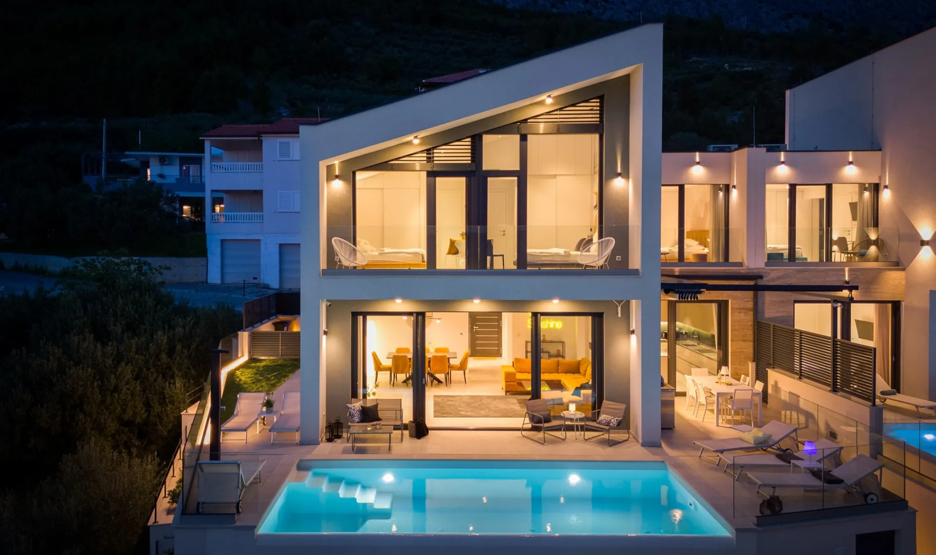 Villa Sunshine am Abend, die beleuchteten Wohnräume hinter der Glasfront